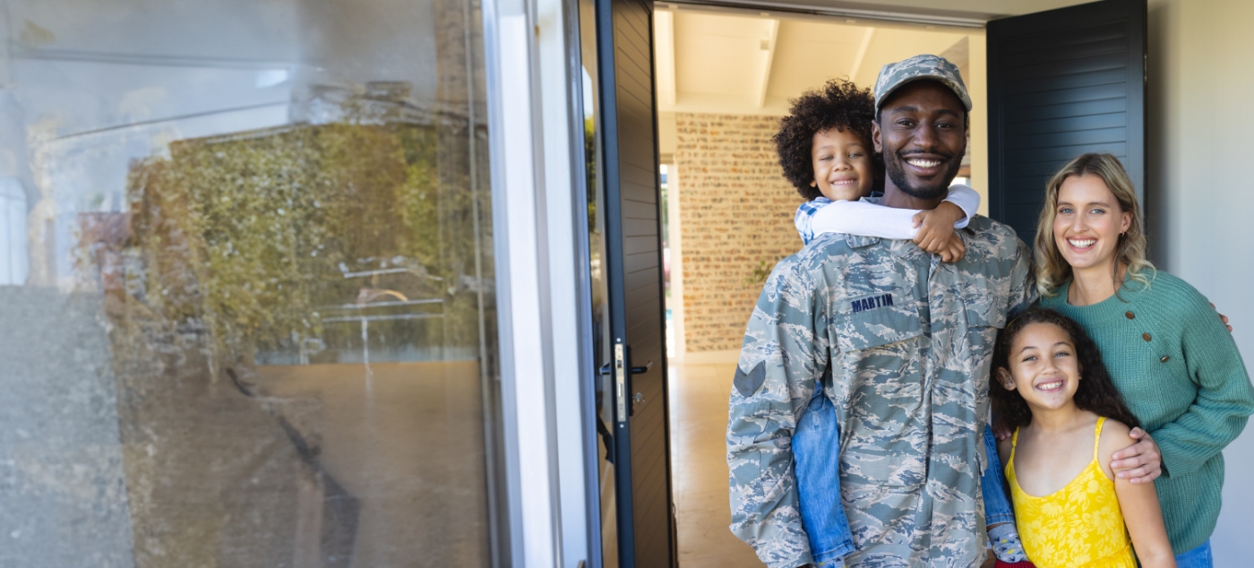 Man in U S military uniform smiling with his family in front of Newark pediatric dental office