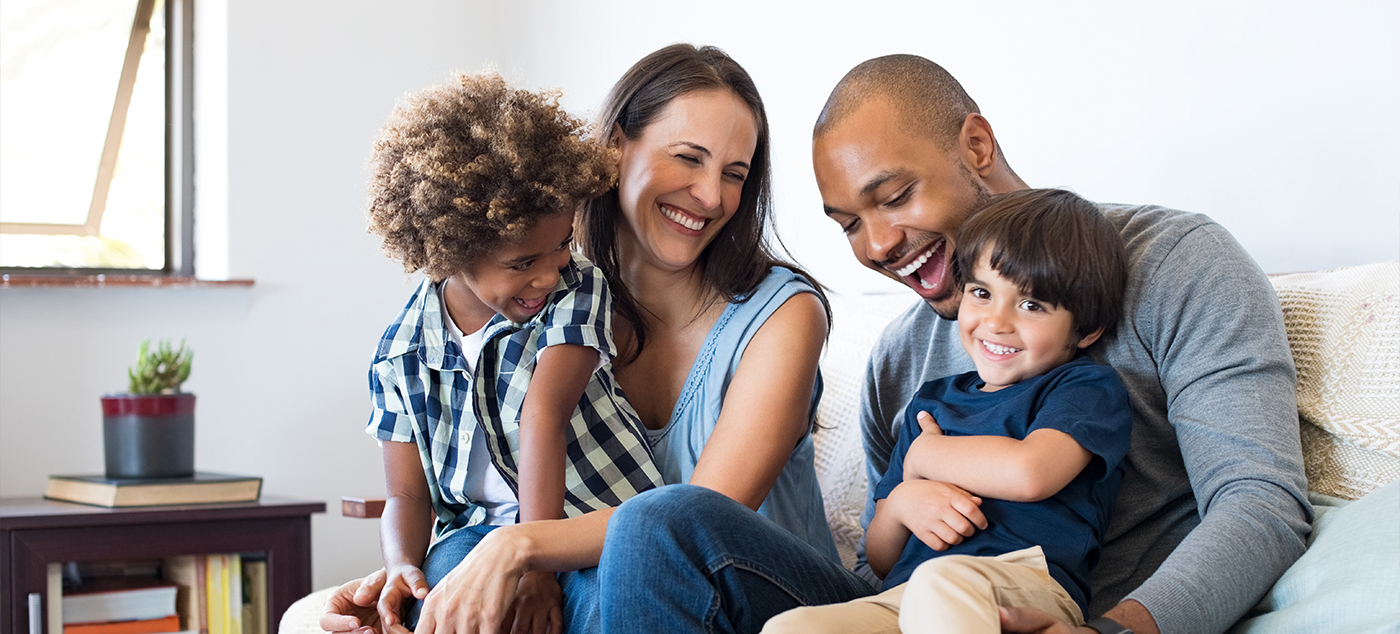 Family of four smiling on couch together