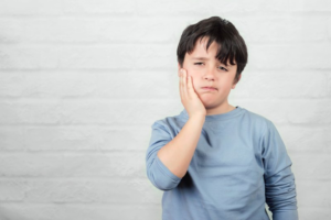 Child holding his jaw because of tooth sensitivity